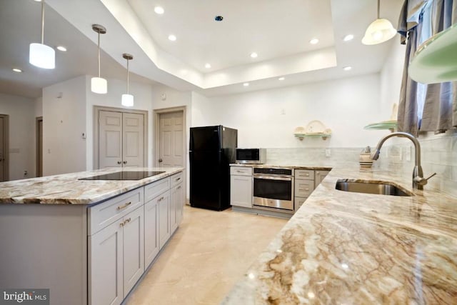 kitchen featuring tasteful backsplash, sink, hanging light fixtures, light stone counters, and black appliances