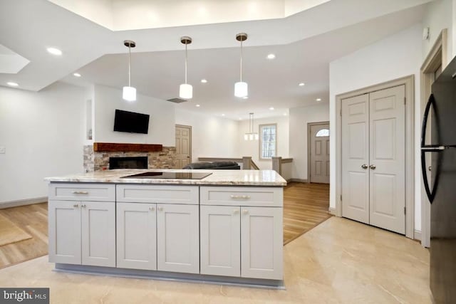 kitchen featuring light stone counters, decorative light fixtures, black appliances, and white cabinets