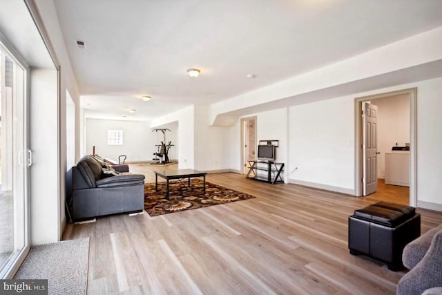 living room with washer / dryer and light wood-type flooring