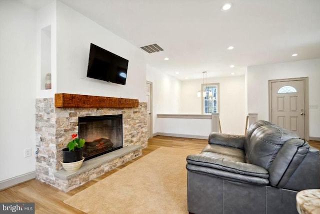 living room featuring a stone fireplace and light wood-type flooring