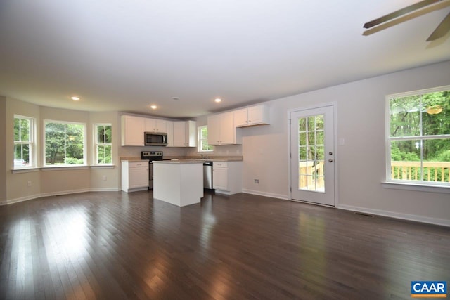 kitchen featuring white cabinetry, dark wood-type flooring, stainless steel appliances, and a center island