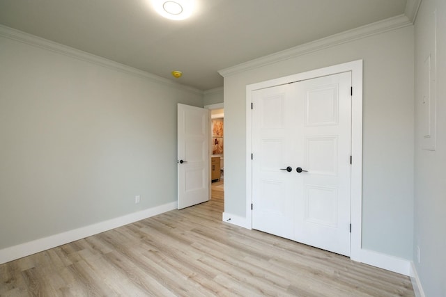 unfurnished bedroom with crown molding, a closet, and light wood-type flooring