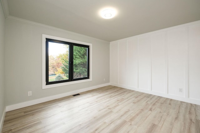 spare room with crown molding and light wood-type flooring