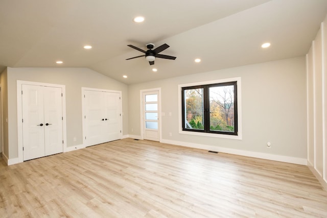 unfurnished bedroom with multiple closets, ceiling fan, lofted ceiling, and light hardwood / wood-style floors