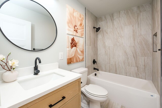 full bathroom featuring tiled shower / bath, vanity, and toilet