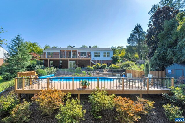 view of swimming pool with a fenced in pool, a water slide, fence, a storage shed, and an outdoor structure