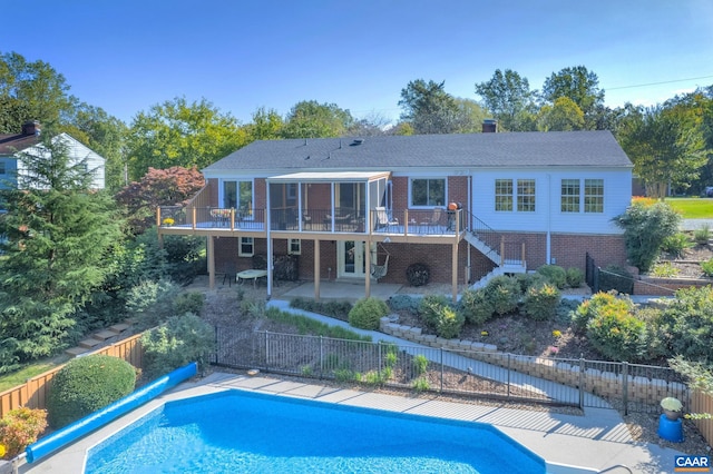 rear view of house with a deck, a patio, fence, brick siding, and stairs