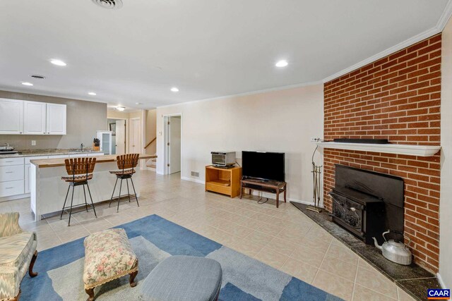 living room featuring light tile patterned floors, baseboards, ornamental molding, and recessed lighting