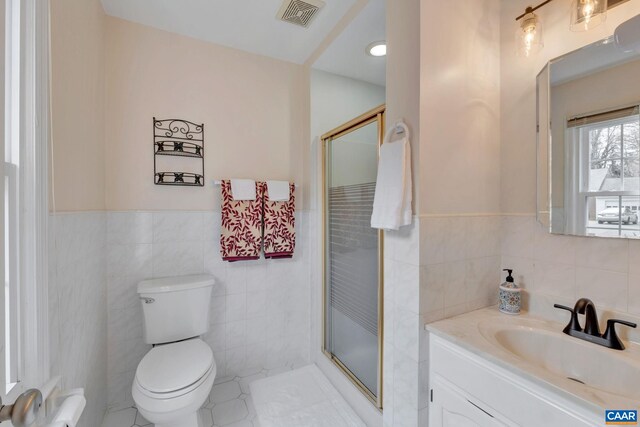 full bathroom with visible vents, vanity, tile walls, and a shower stall