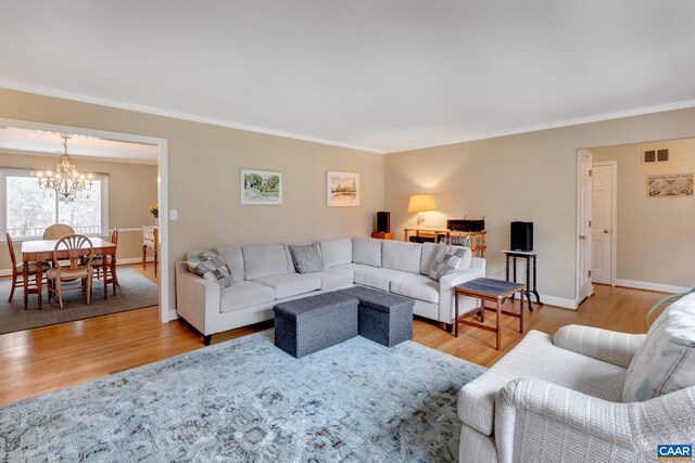 living room with visible vents, an inviting chandelier, wood finished floors, and crown molding