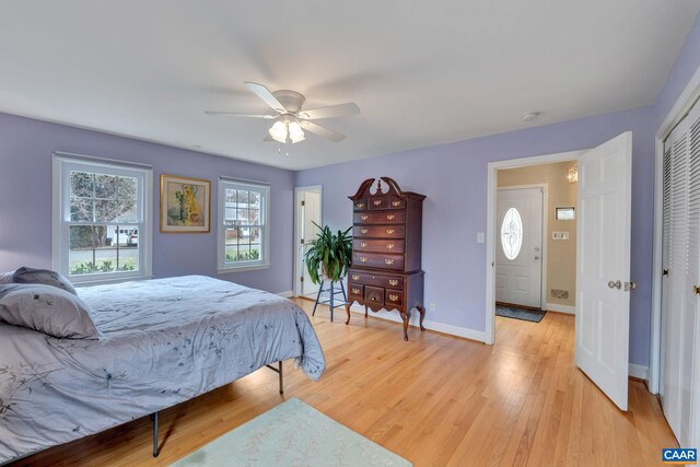 bedroom with a closet, baseboards, light wood-style floors, and a ceiling fan