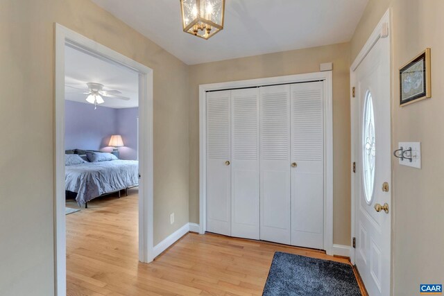 foyer entrance with a chandelier, baseboards, and light wood-style flooring