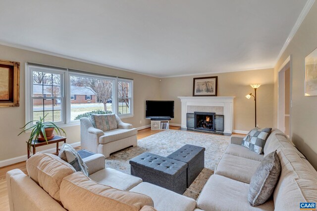 living room featuring light wood finished floors, a fireplace with flush hearth, crown molding, and baseboards