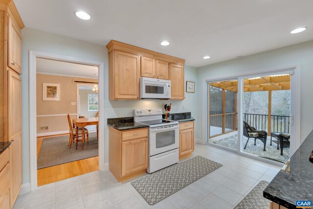 kitchen featuring white appliances, dark stone countertops, light brown cabinets, and recessed lighting