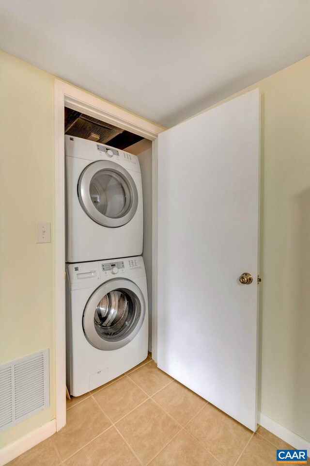 washroom with laundry area, stacked washer and dryer, light tile patterned floors, and visible vents