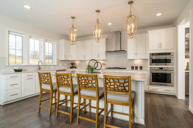 kitchen with appliances with stainless steel finishes, a center island, white cabinets, and wall chimney exhaust hood