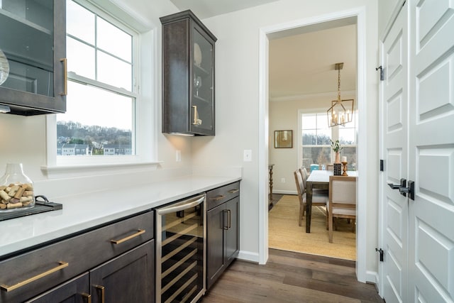 bar with wine cooler, crown molding, dark brown cabinets, dark hardwood / wood-style floors, and pendant lighting