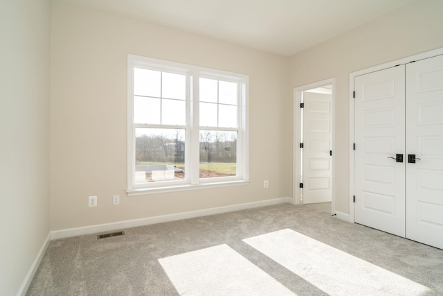 unfurnished bedroom featuring light carpet and a closet