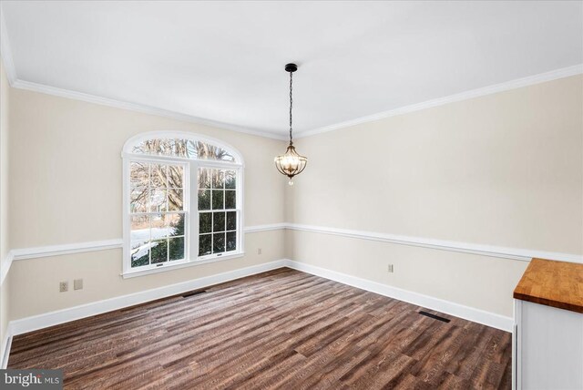 unfurnished dining area featuring a notable chandelier, crown molding, and dark hardwood / wood-style floors