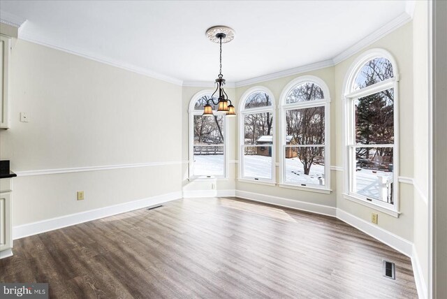 unfurnished dining area with crown molding, dark wood-type flooring, and an inviting chandelier