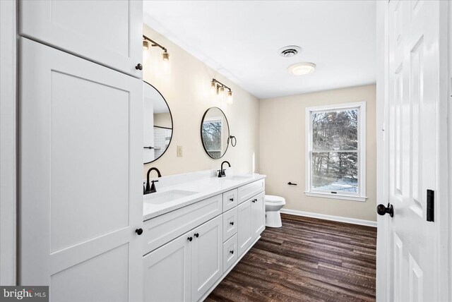 bathroom with wood-type flooring, vanity, and toilet