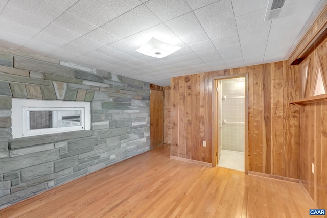 basement with wooden walls and light hardwood / wood-style flooring