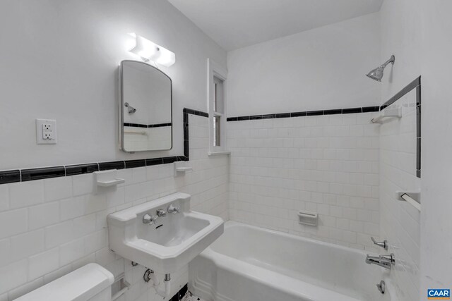 full bathroom with tiled shower / bath combo, sink, tile walls, and toilet