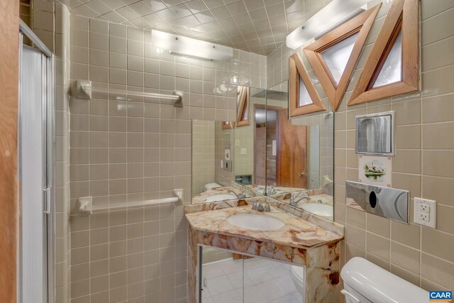 bathroom with tile walls, sink, tile patterned floors, and toilet