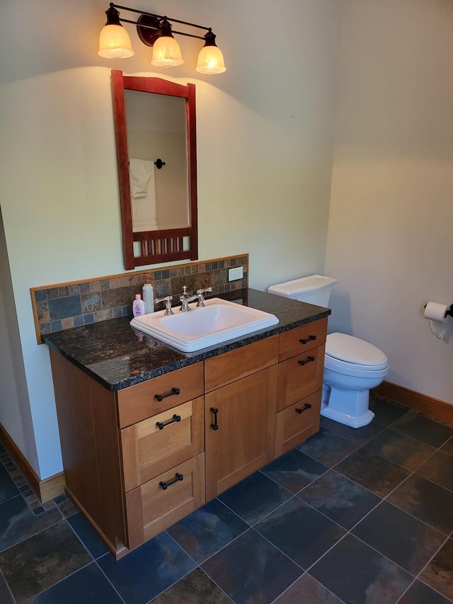 bathroom featuring vanity, toilet, and backsplash