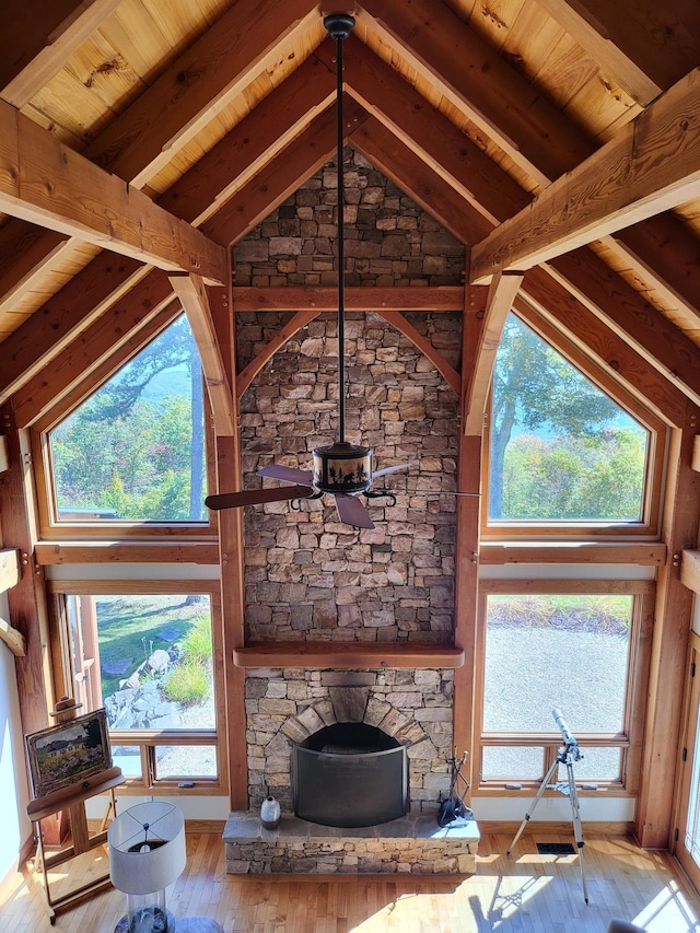 unfurnished living room with beamed ceiling, a wealth of natural light, high vaulted ceiling, and light hardwood / wood-style flooring