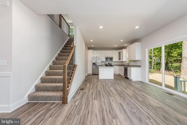 kitchen with sink, white cabinets, a center island, stainless steel appliances, and light hardwood / wood-style flooring