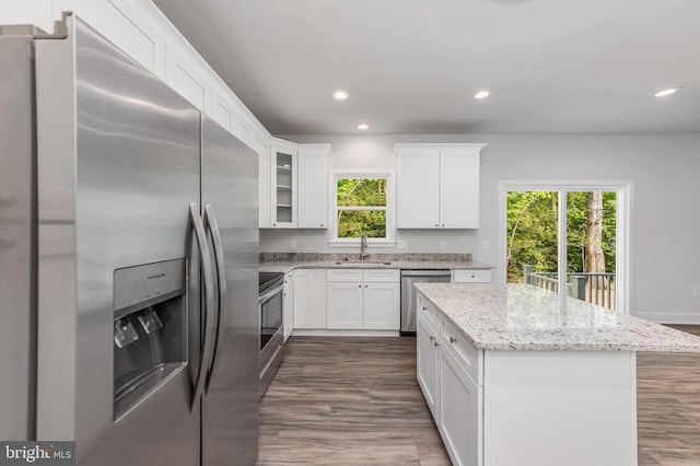 kitchen with dark wood-type flooring, sink, light stone counters, white cabinetry, and appliances with stainless steel finishes