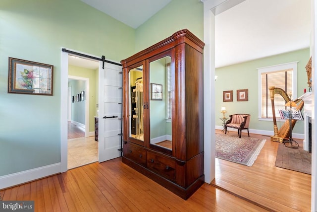 corridor with a barn door and light hardwood / wood-style floors