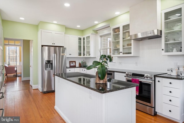 kitchen featuring a kitchen island, appliances with stainless steel finishes, white cabinetry, dark stone countertops, and light hardwood / wood-style flooring