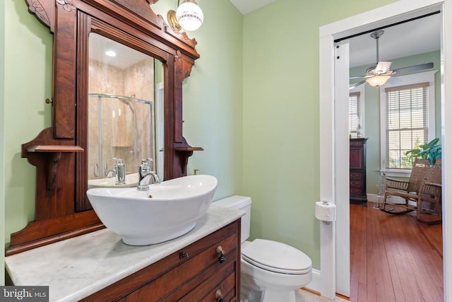 bathroom featuring hardwood / wood-style flooring, vanity, an enclosed shower, ceiling fan, and toilet