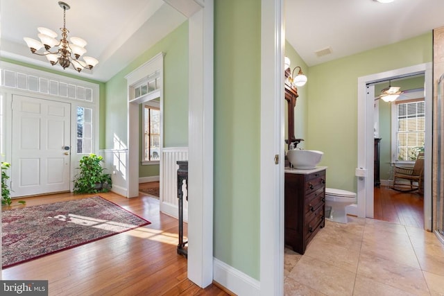 tiled foyer entrance with sink and a notable chandelier