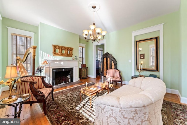 living room with a premium fireplace, a notable chandelier, and light hardwood / wood-style floors