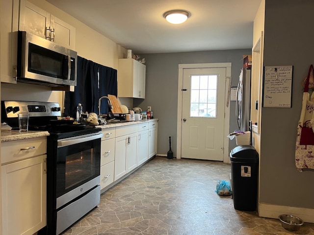 kitchen featuring light stone counters, sink, stainless steel appliances, and white cabinets