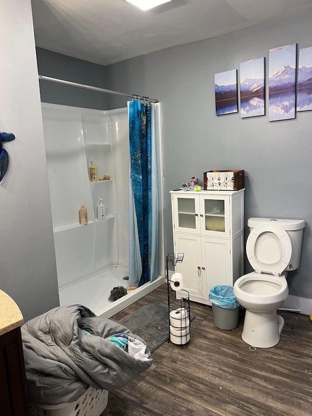bathroom featuring wood-type flooring, toilet, and a shower with shower curtain