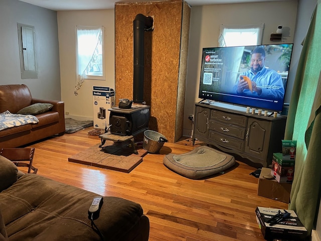 living room with wood-type flooring, a wood stove, and electric panel