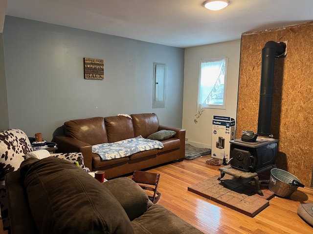 living room with hardwood / wood-style floors, electric panel, and a wood stove