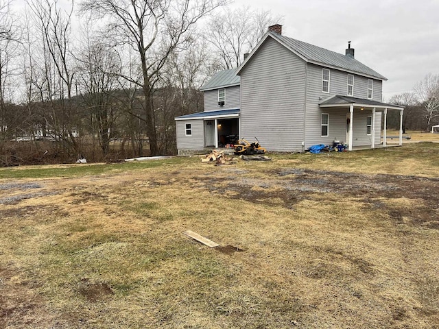 rear view of property featuring a porch and a yard