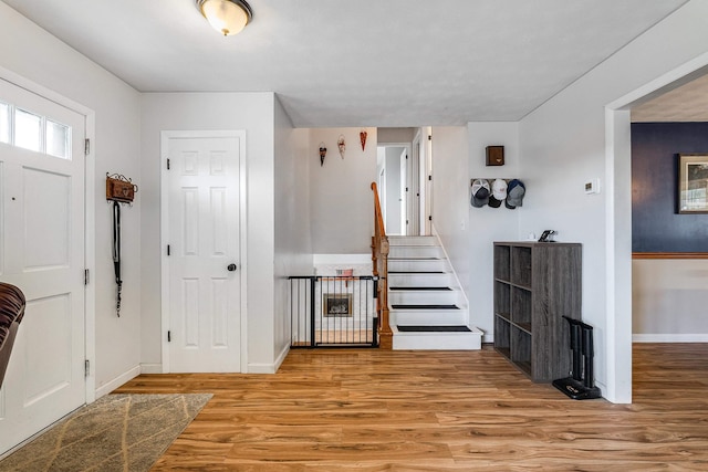 entrance foyer with stairway, wood finished floors, and baseboards