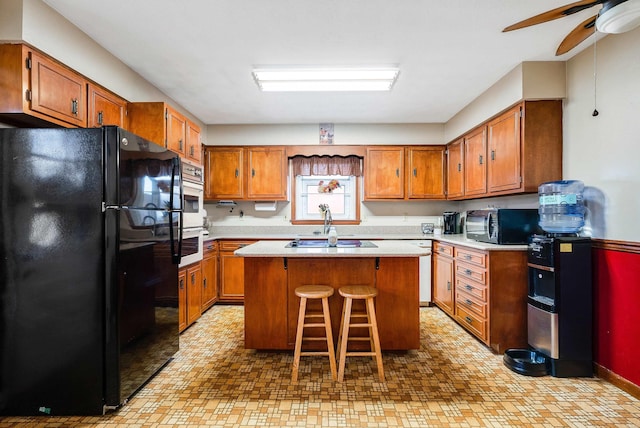 kitchen with a breakfast bar area, light countertops, brown cabinetry, a kitchen island, and black appliances