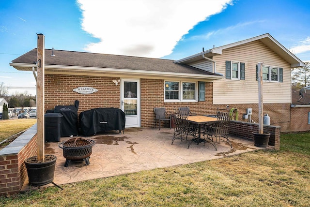 rear view of property with a patio area, an outdoor fire pit, and brick siding