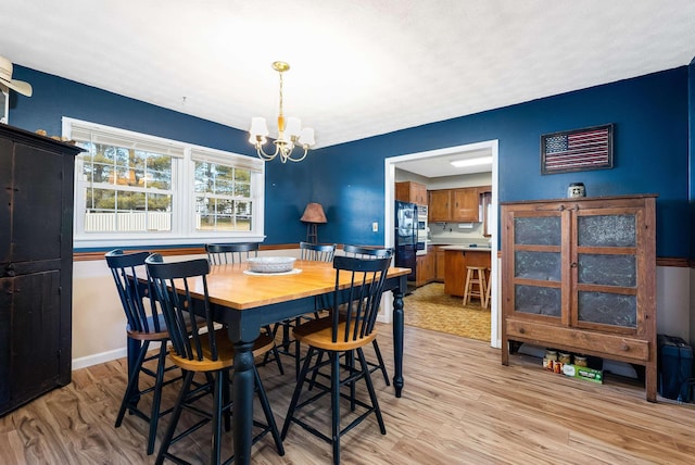 dining area featuring an inviting chandelier, light wood-style flooring, and baseboards