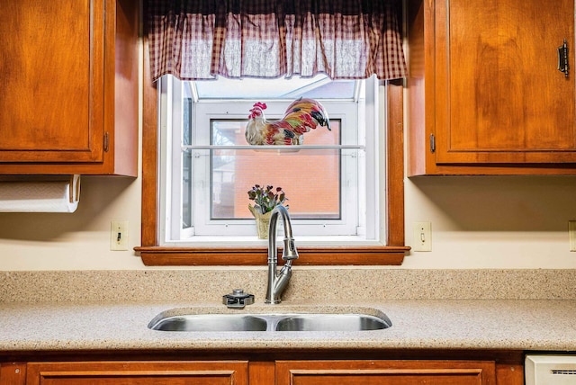 kitchen featuring brown cabinetry, light countertops, and a sink