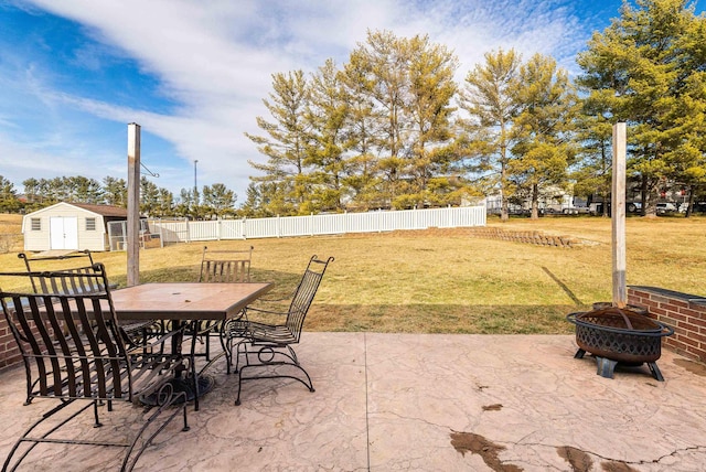 view of patio / terrace featuring an outdoor fire pit, a storage shed, an outdoor structure, fence, and outdoor dining space