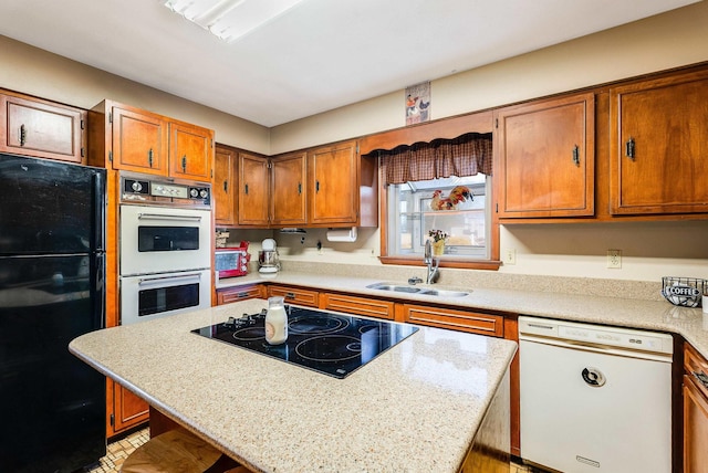 kitchen featuring black appliances, brown cabinetry, and a sink