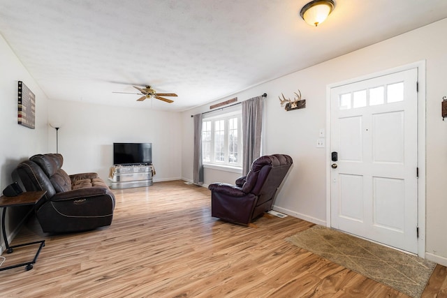 living room with a ceiling fan, light wood-style flooring, and baseboards